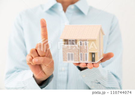 戸建ての住宅模型を持って人差し指を立てるミドル女性 110744074