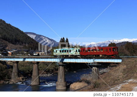 冠雪の大日ヶ岳をバックに長良川を渡る長良川鉄道 110745173
