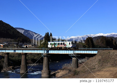 冠雪の大日ヶ岳をバックに長良川を渡る長良川鉄道 110745177