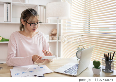 Young Businesswoman presses a calculator to calculate income tax and corporate income in a private office, Statistical graphs of investing in real estate, Finance, Accounting, Tex, Work for home. Young Businesswoman presses a calculator to calculate income tax and corporate income in a private office, Statistical graphs of investing in real estate, Finance, Accounting, Tex, Work for home. 110746074