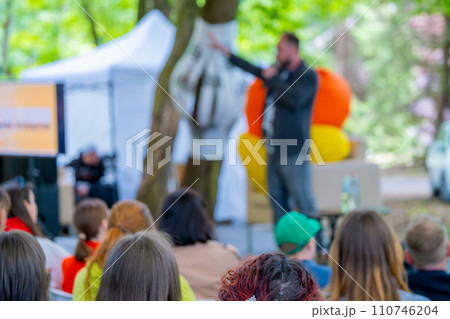 Outdoor event with speaker engaging audience in public park Outdoor event with speaker engaging audience in public park 110746204