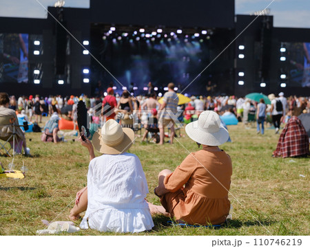 Friends enjoying a live music festival outdoors on a sunny day 110746219