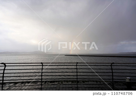 護岸の手すりと突堤、遠くに虹を望む 護岸の手すりと突堤、遠くに虹を望む 110748706