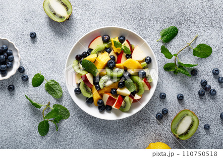 Fruit and berry salad with mango, kiwi, apple, blueberry and fresh mint leaves. Healthy food, diet. Top view 110750518