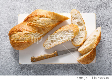 Bread, baguette sliced on a board, top view Bread, baguette sliced on a board, top view 110750530