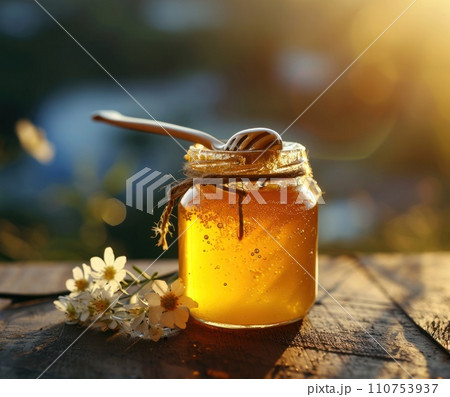 jar of honey with a spoon stuck in 110753937