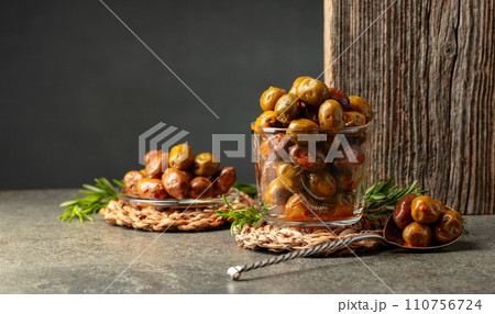 Spicy olives in a glass bowl on a stone table. 110756724