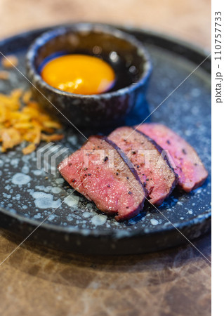 Close-up of Beef tongue meat on plate and egg yolk served as Fine dining in Restaurant. 110757733