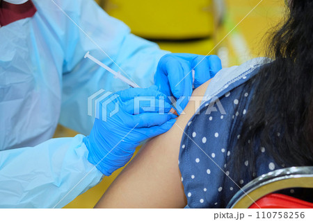 Doctor hands who is vaccinating on upper arm of people 110758256
