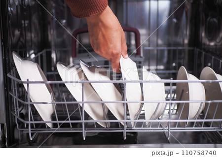 A young woman opens takes out clean white utensils. A young woman opens takes out clean white utensils. 110758740