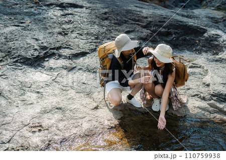 Happy LGBT Lesbian couple Travelers Hiking with Backpacks in waterfall Trail. LGBT Lesbian Couple Hikers with backpacks walks in mountains in vacation 110759938