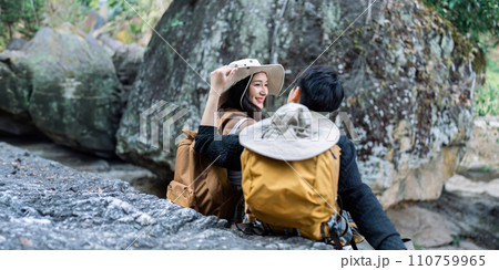 Lesbian couple relaxing together on rock at a hiking trail While traveling together on a hiking trail 110759965