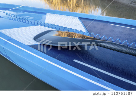 detail of stand up paddleboard with a paddle and safety leash 110761587