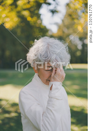 公園の60代女性　眉間を押さえる 110761770