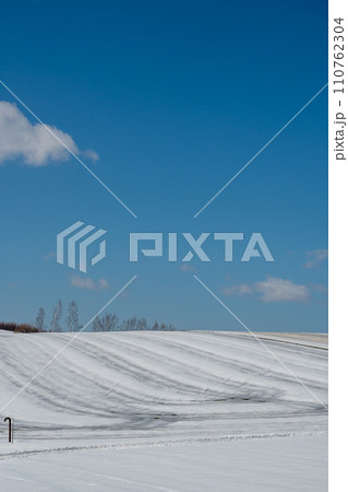 融雪剤が撒かれた雪の畑と青空 110762304