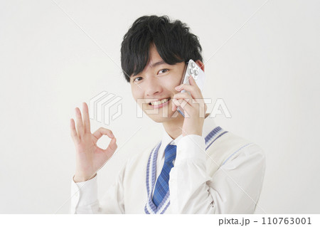 スマートフォンで電話しながらOKサインをする男子高校生　白背景 110763001