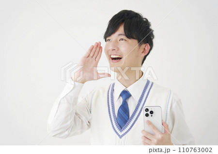 スマートフォンを持って話しかける男子高校生　白背景 110763002
