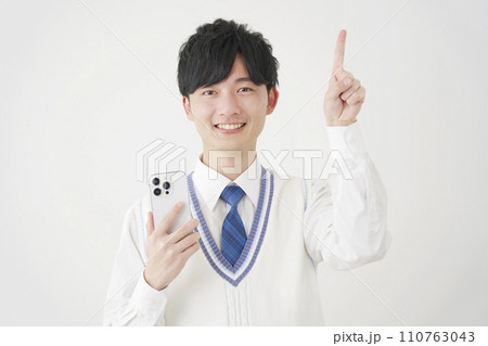 スマートフォンを持って上を指差す男子高校生　白背景 110763043