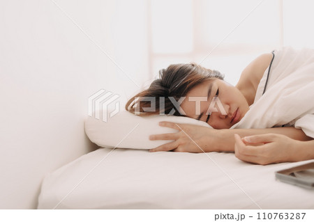 Sad and depressed Asian woman lying awake in the morning to weak to get up form bed. Sad and depressed Asian woman lying awake in the morning to weak to get up form bed. 110763287