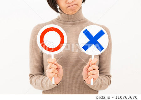 丸バツプレートを持って悩むミドル女性 110763670