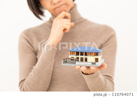 戸建ての住宅模型を持って悩むミドル女性 110764071