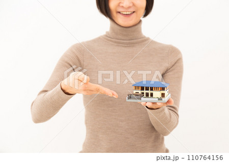 戸建ての住宅模型を持って笑うミドル女性 110764156