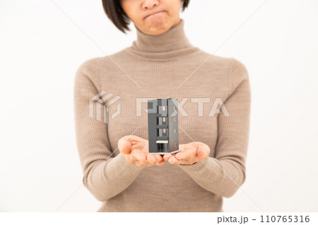 ビルの住宅模型を持って悩むミドル女性 ビルの住宅模型を持って悩むミドル女性 110765316