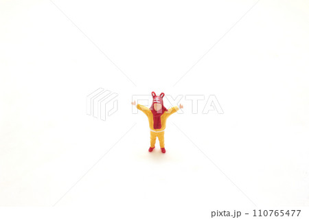 a Toy Figure in Yellow with Red Hat on White Background 110765477