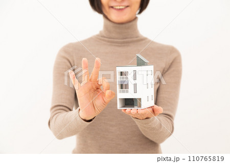 戸建ての住宅模型を持って丸サインをするミドル女性 110765819