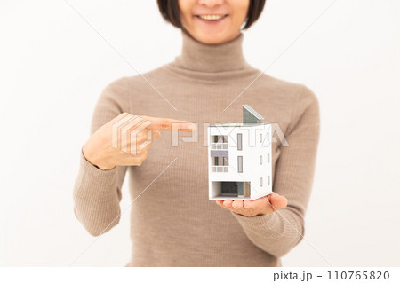 戸建ての住宅模型を指差して笑うミドル女性 110765820