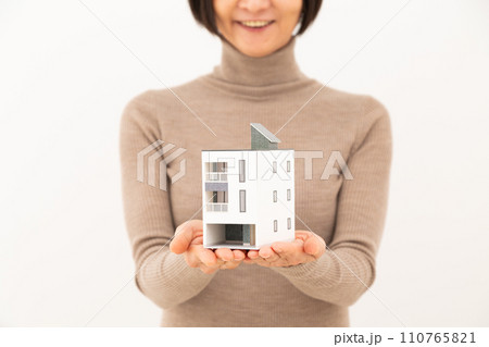 戸建ての住宅模型を持って笑うミドル女性 110765821