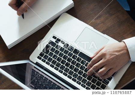 パソコン作業をしながらメモを取るビジネスマンの手元 110765887