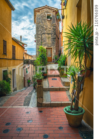 Cozy narrow street decorated with flowers and green plants, France 110766899