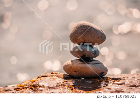 Pyramid stones on the seashore on a sunny day on the blue sea background. Happy holidays. Pebble beach, calm sea, travel destination. Concept of happy vacation on the sea, meditation, spa, calmness. 110769025