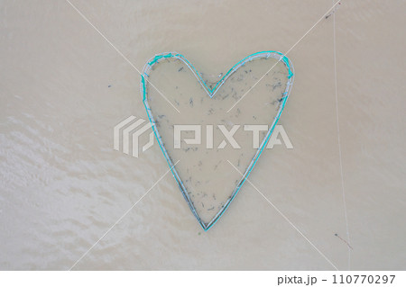 Aerial view of heart shape fishing trap net in canel urban city village town houses, lake or river. Nature landscape fisheries and fishing tools at Pak Pha, Thailand. Aquaculture farming. Love Aerial view of heart shape fishing trap net in canel urban city village town houses, lake or river. Nature landscape fisheries and fishing tools at Pak Pha, Thailand. Aquaculture farming. Love 110770297