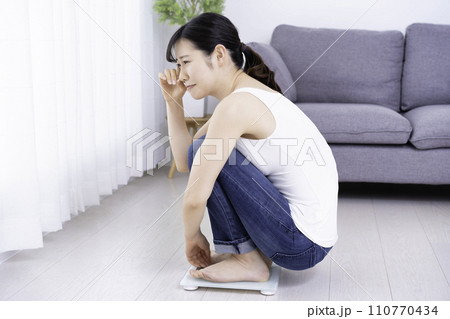 体重を計ってショックを受ける女性 体重を計ってショックを受ける女性 110770434