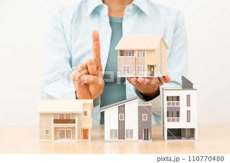 戸建ての住宅模型を持って人差し指を立てるミドル女性 110770480