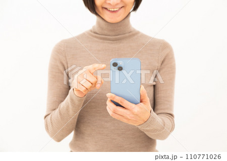 スマホを操作しながら微笑むミドル女性 110771026