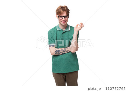 young caucasian male student with red hair and a tattoo on his forearm wearing glasses dressed in a 110772765