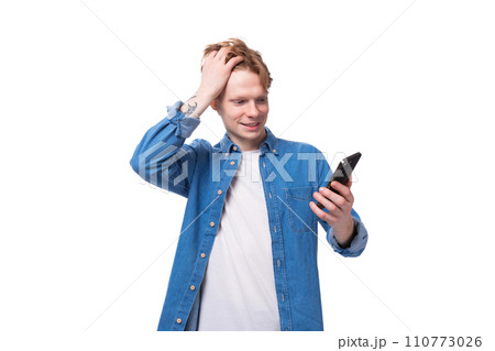 young red-haired guy smiling looking into a smartphone on a white background young red-haired guy smiling looking into a smartphone on a white background 110773026