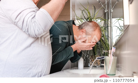 Mature homosexual couple cleaning face and teeth in the toilet at home 110777054