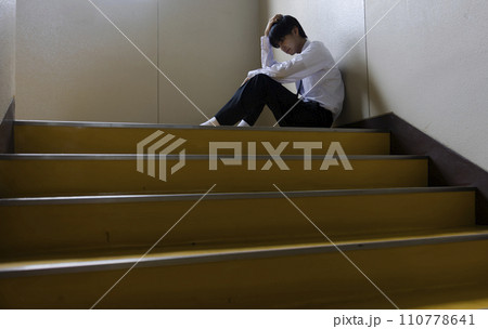 階段に座り悩む男子学生 110778641