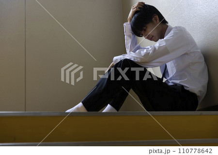 階段に座り悩む男子学生 110778642