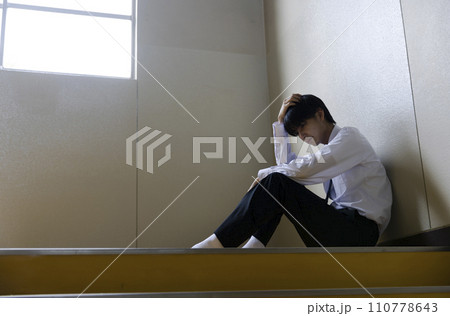 階段に座り悩む男子学生 110778643