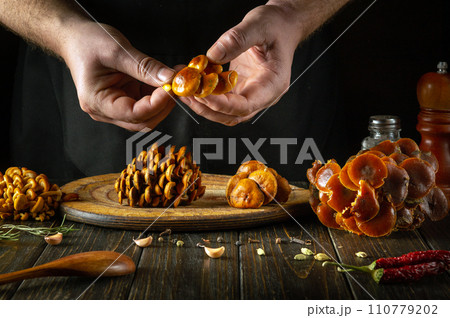 A chef cleans fresh raw mushrooms with his hands in a restaurant kitchen. Concept of preparing dietary Flammulina velutipes for lunch 110779202