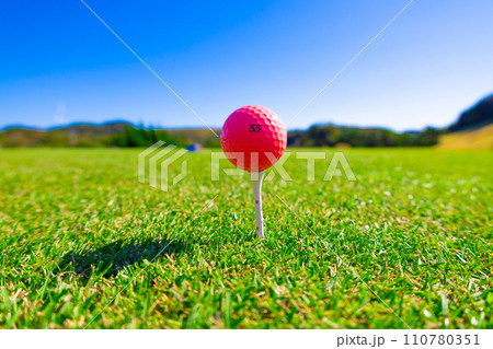 青空のゴルフ場・ティーグラウンドにティーアップされたかわいいピンクのゴルフボール（千葉県富津市） 110780351