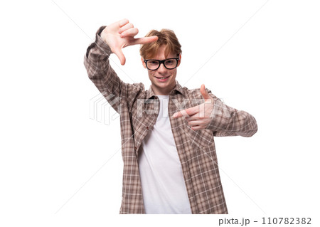 young smart man with red golden hair in glasses and a shirt gesturing with his hands on a white 110782382