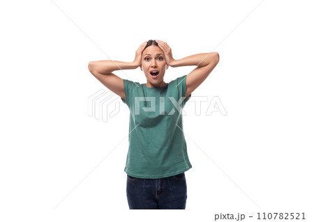 30 year old slender European brunette woman with a ponytail dressed in a green T-shirt and jeans 110782521