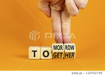 Tomorrow we will together symbol. Businessman turns wooden cubes and changes the word together to tomorrow. Beautiful orange background, copy space. Business and tomorrow we are together concept. 110782798