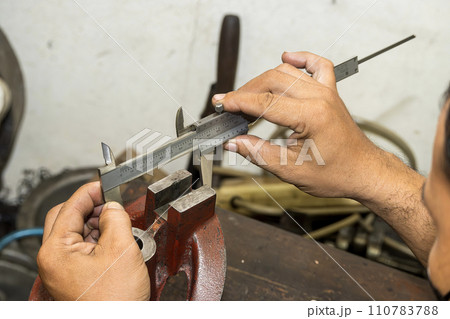 Close up scene the machine operator measuring dimension of cast iron parts by Vernier caliper. Close up scene the machine operator measuring dimension of cast iron parts by Vernier caliper. 110783788